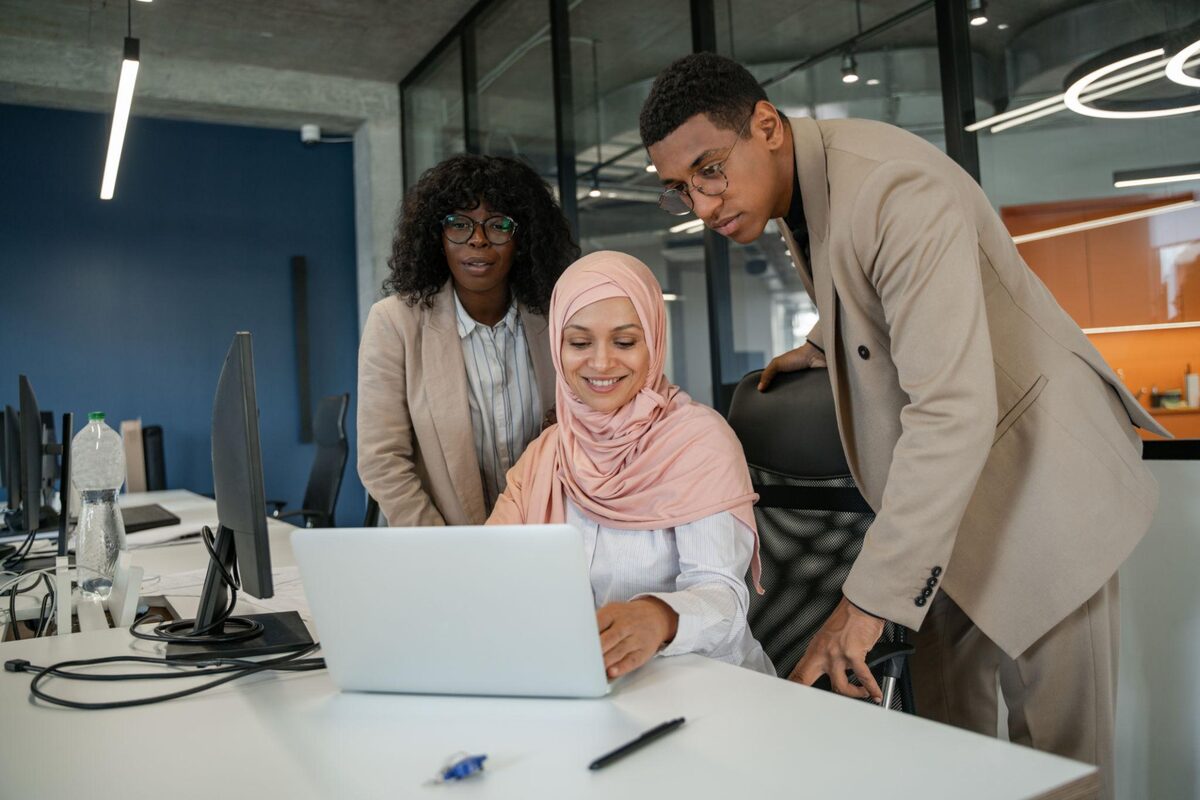 A diverse team collaborating around a laptop in an office